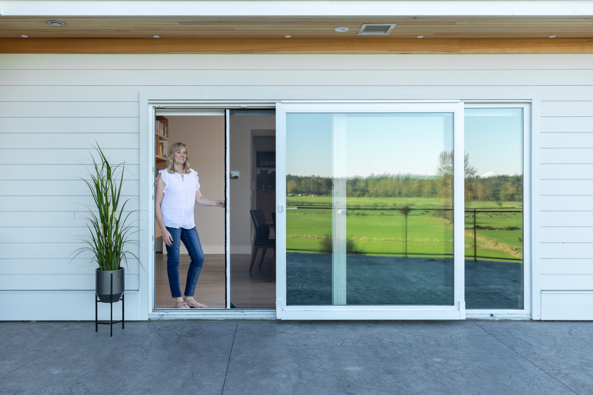 Woman opens her Phantom Retractable Screen Door to let fresh air into her home.