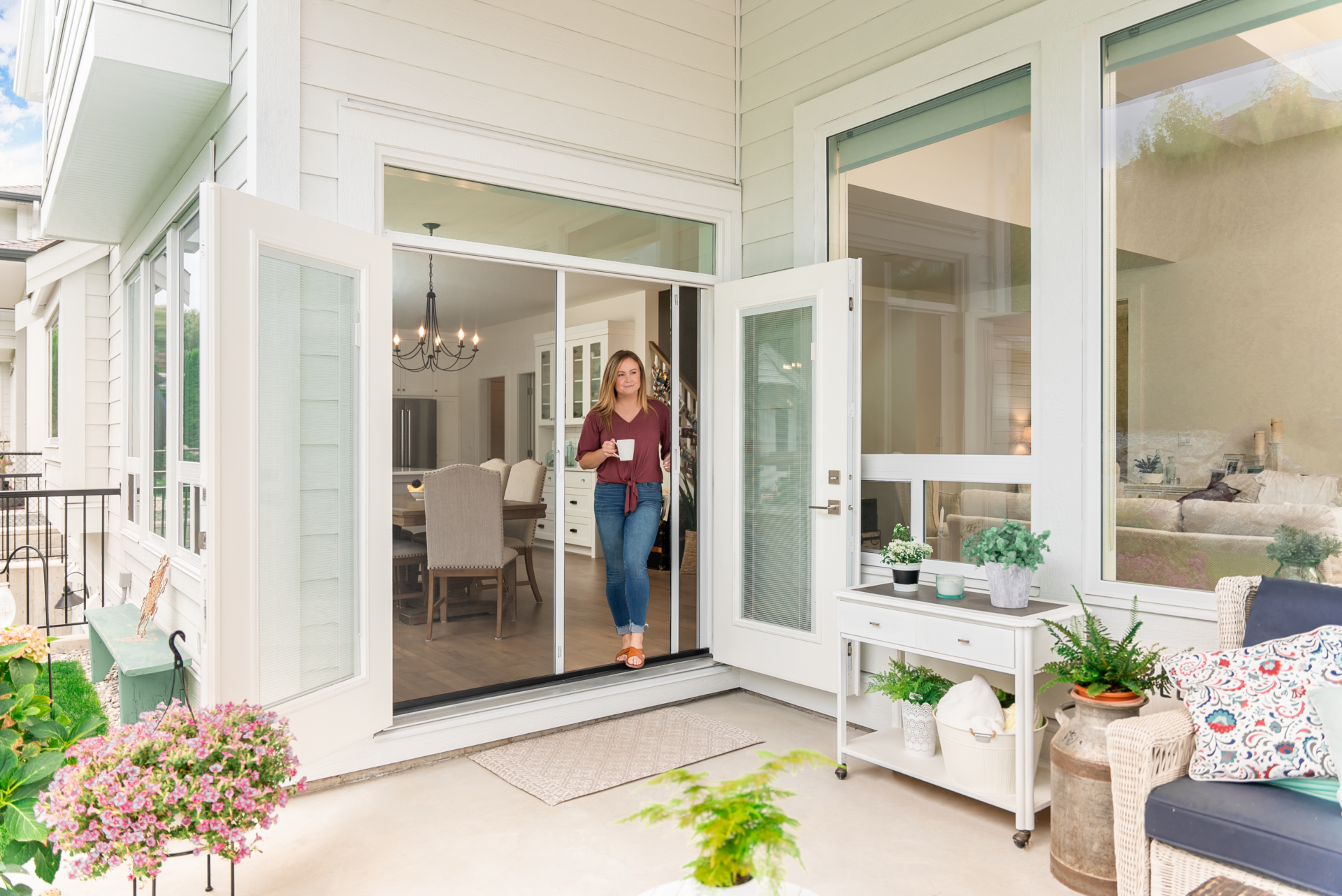 Woman opens her Phantom Retractable Screen on her french doors to let fresh air into her home.