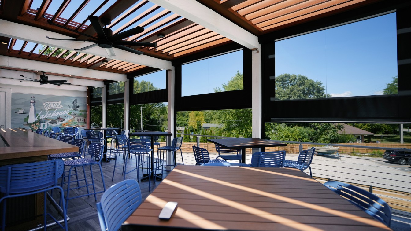 Screening Solutions Ohio installs Phantom Motorized Vinyl onto the upper patio of a restaurant in Lakeside Marblehead, Ohio called Red’s Lakehouse. The retractable clear vinyl units drop down and seal in the upper deck and bar area, keeping out insects, wind, rain, and snow, perfectly for the Lake Erie climate. The vinyl moves up and down and retracts away when not needed, allowing the restaurant to maintain an open and airy atmosphere. The black and clear vinyl blends with the restaurant’s décor, providing an aesthetic screen option. Guests at Red’s Lakehouse can enjoy dining outdoors with the help of Phantom Screens.